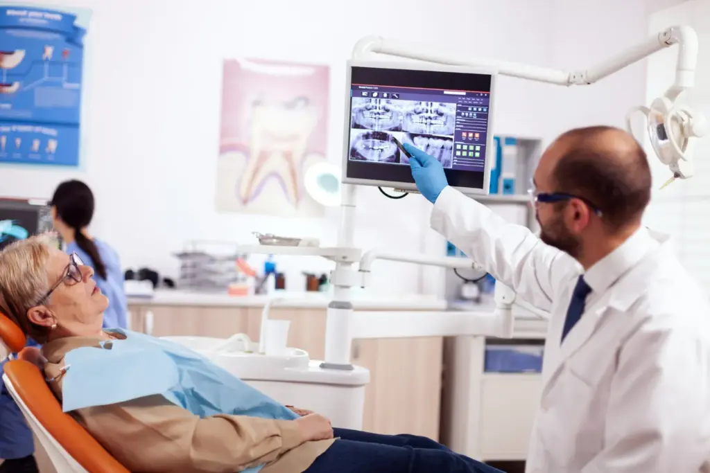 Dentist reviewing a dental X-ray with a patient during an implant assessment to check jawbone and tooth structure.